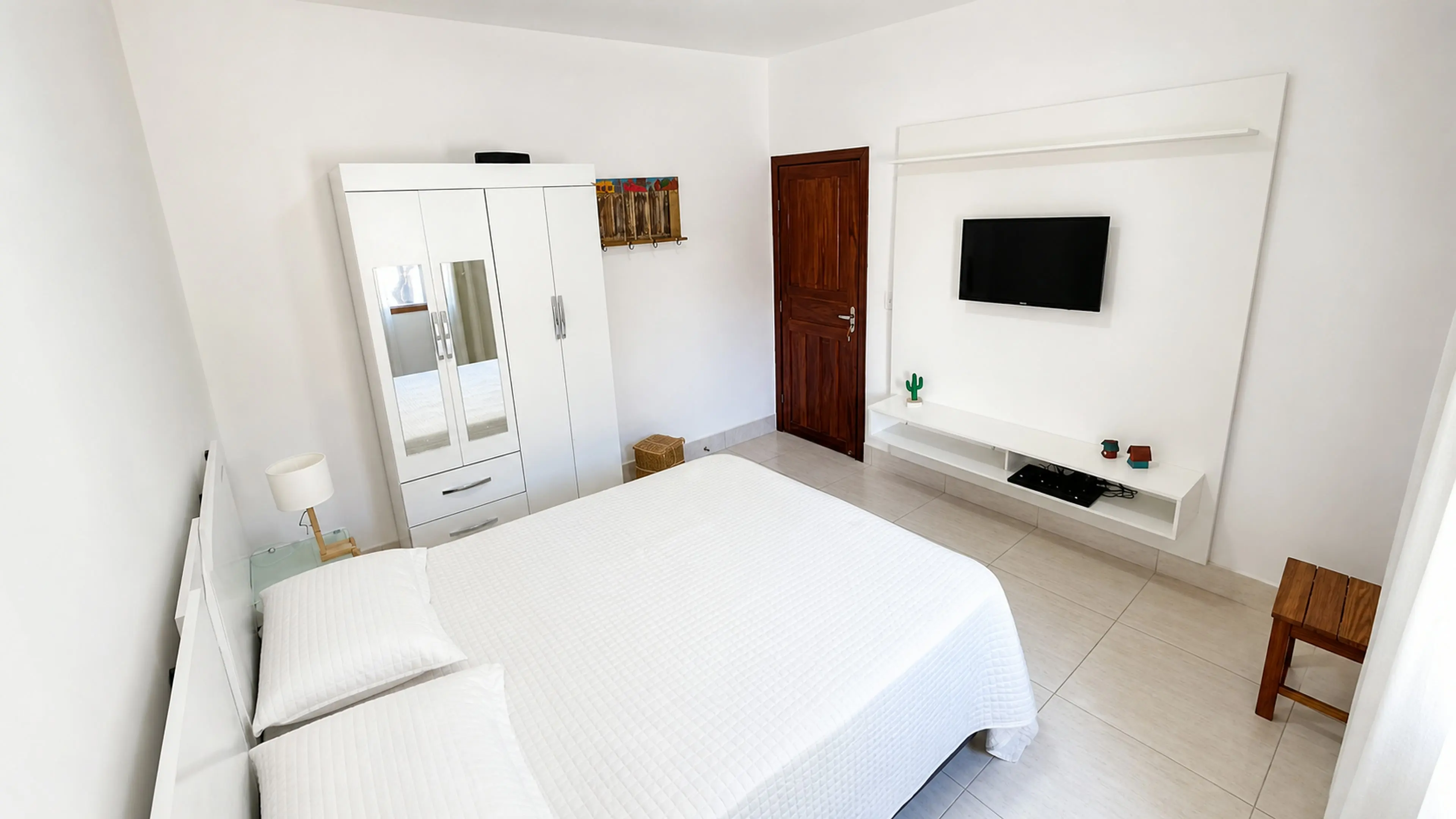 Suíte de casal com televisão e ar-condicionado na Casa Paulo Filho e Neto